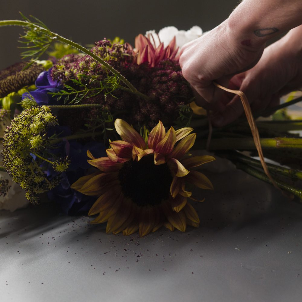 Fleuriste FLWR composant un bouquet à la main dans l’atelier parisien